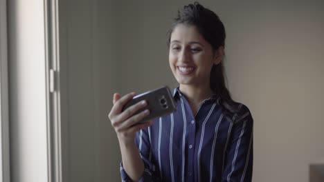 Positive-Latin-girl-saying-Hello-to-smartphone-screen